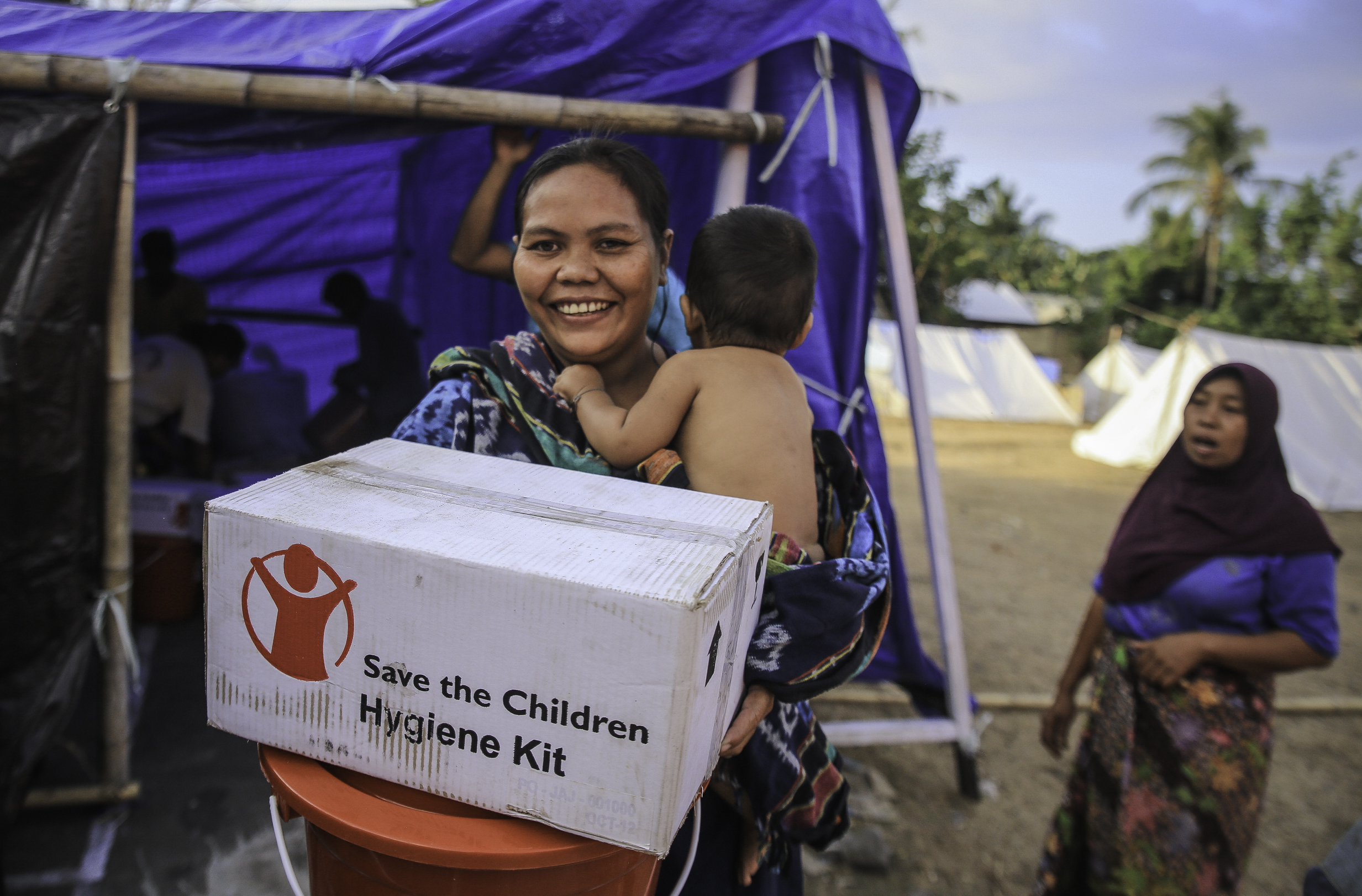 Lady carrying her child and a hygiene kit box